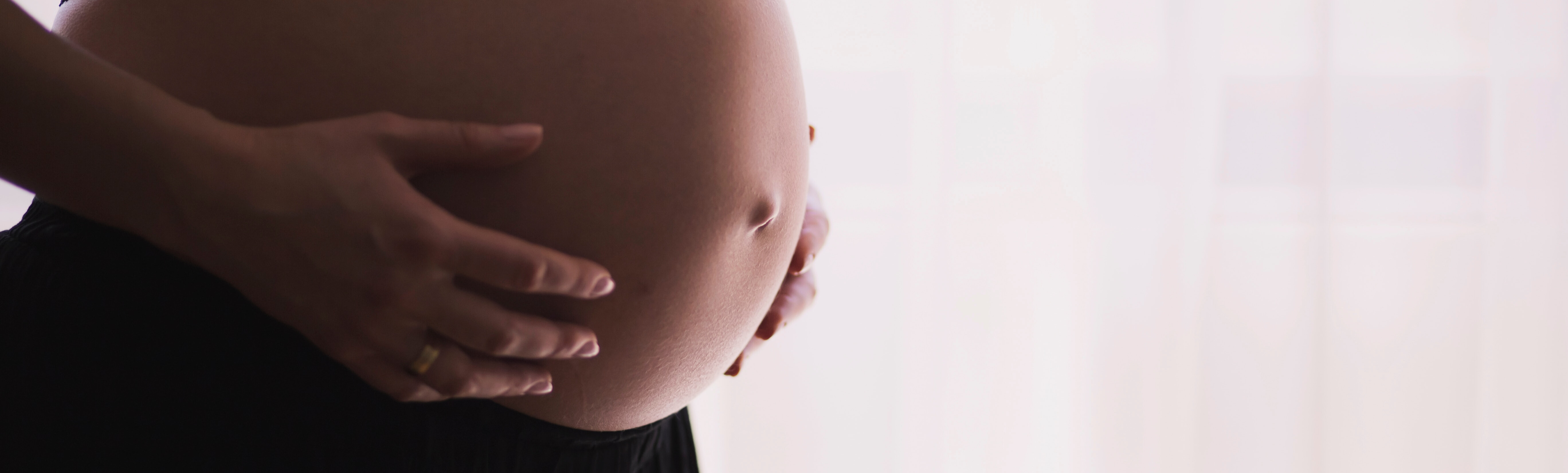 Eine Frau hält ihre Hände auf ihrem schwangeren Bauch