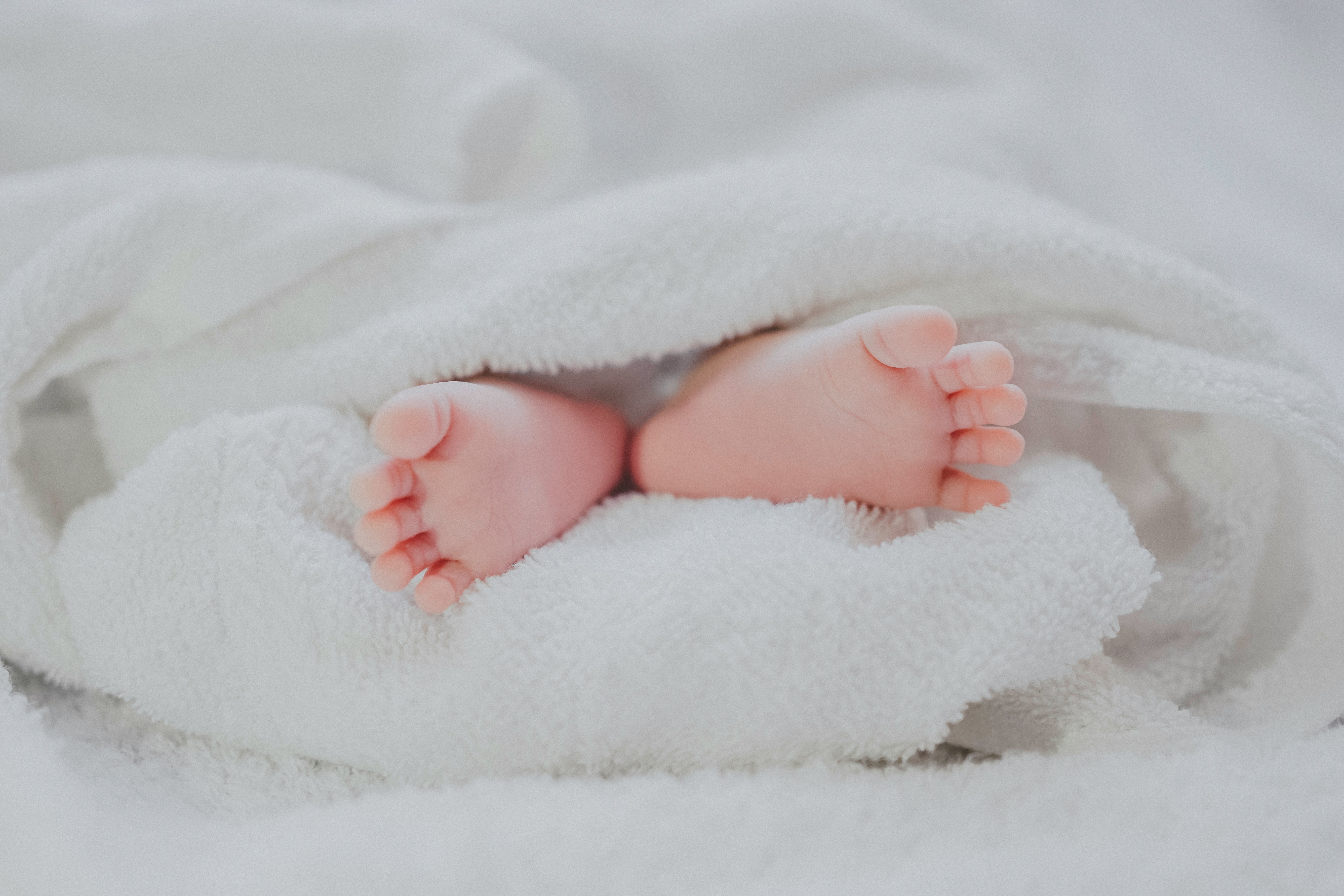 Pinke Babyfüße in einem flauschigen weißen Handtuch
